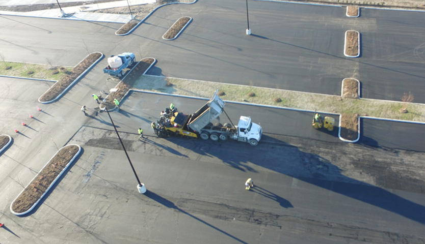 Overhead view of a new parking lot under construction with workers and equipment.